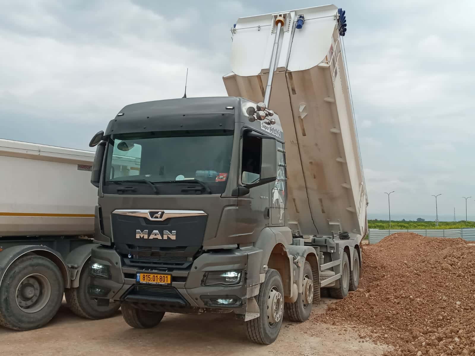 משאית רכינה תוצרת MAN בצבע אפור בזמן פריקה